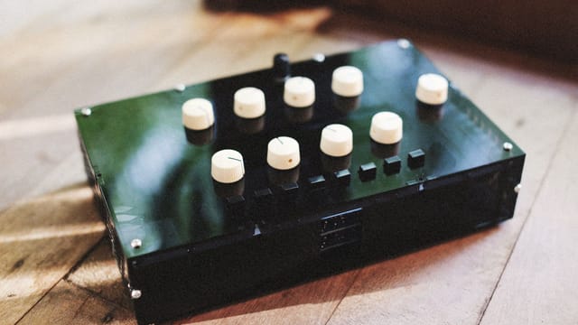 Close-up of vintage audio equipment with multiple control dials on a wooden surface.