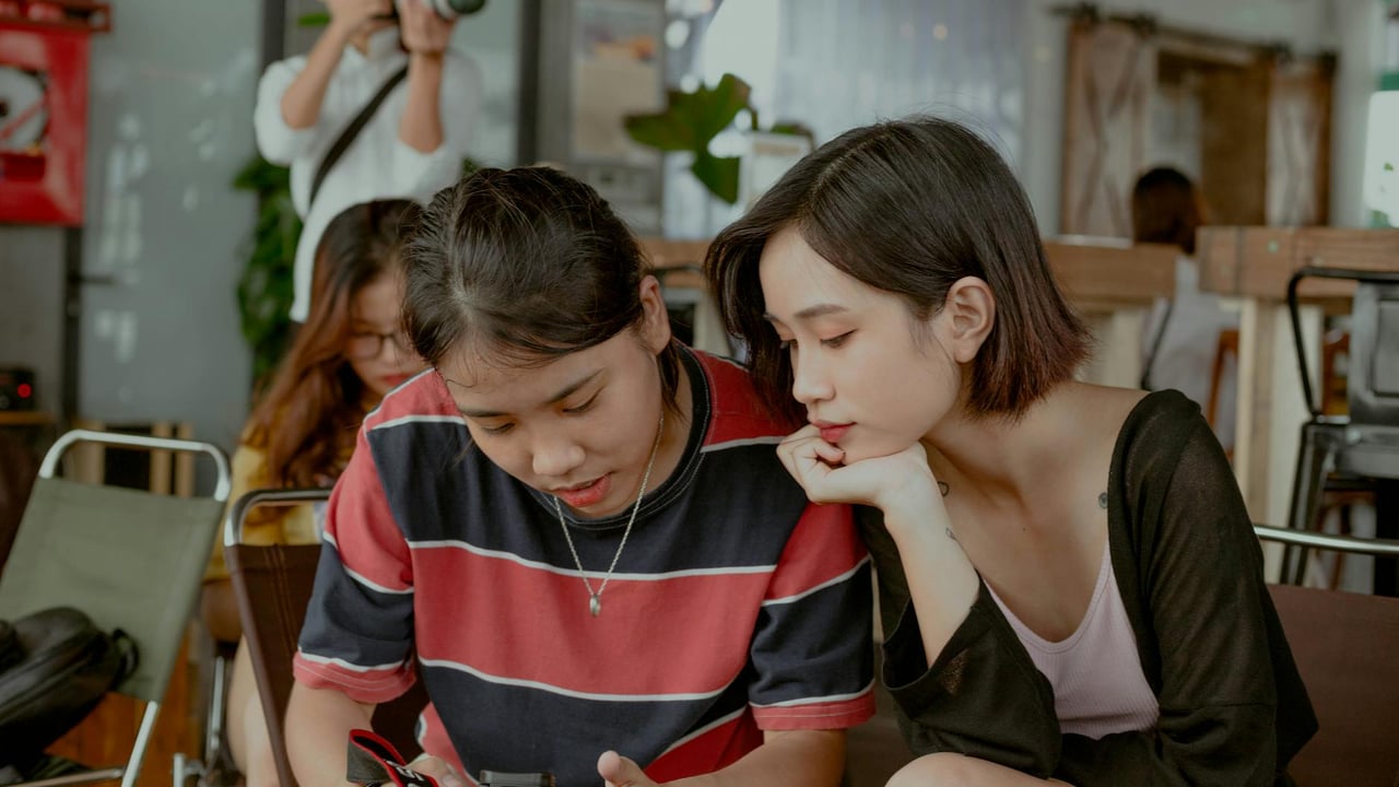 Group of young friends enjoying photography indoors, reviewing shots.