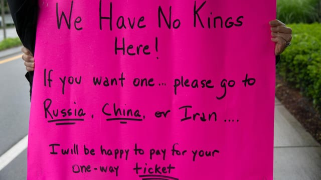 A vibrant protest sign in South Kingstown, Rhode Island, advocating against monarchies with political messaging.