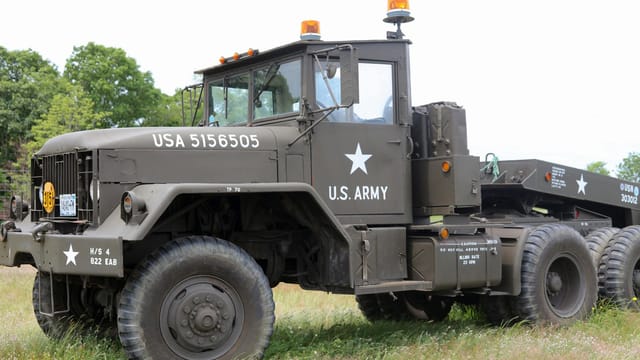 Parked U.S. Army military vehicle in a grassy New York field during daylight.