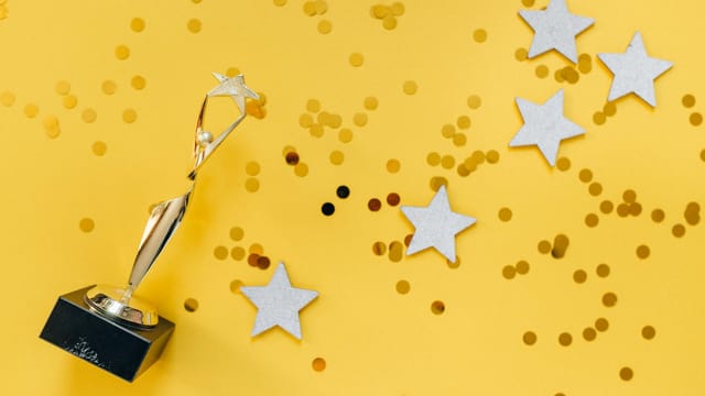 Shiny golden trophy and stars on a vibrant yellow background, symbolizing success and victory.