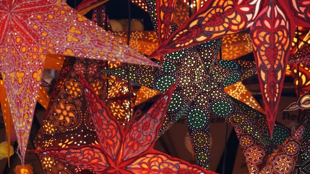 Colorful illuminated star-shaped lanterns create a festive Christmas market ambiance.