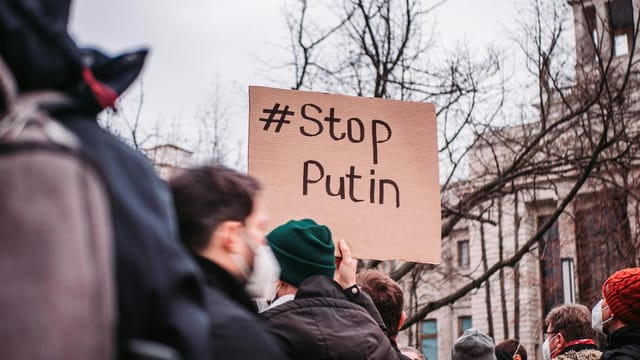 People in Berlin protest against Putin with anti-war signs, showing unity for peace.