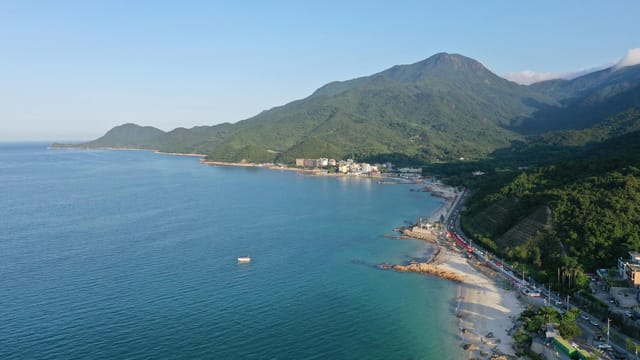Breathtaking drone shot of the Shenzhen coastline with lush mountains and a serene beach.