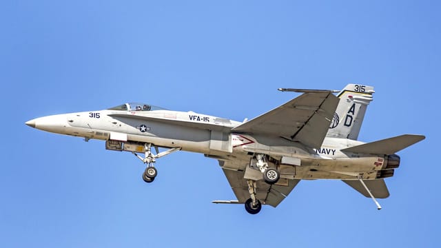 F/A-18C Hornet jet of the US Navy with landing gear deployed, flying over Florida.