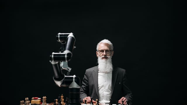 A bearded man in suit playing chess with robotic arm, showcasing AI strategy.