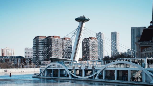 Stunning view of modern architecture and skyline in Tianjin, China with blue skies and river reflections.