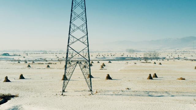 A vast snowy field with a transmission tower in Jilin, China.