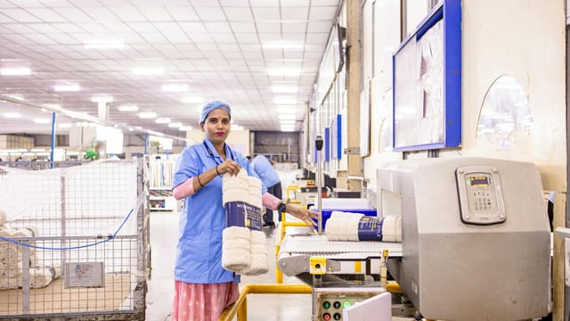 Female textile worker organizing products in a factory setting.