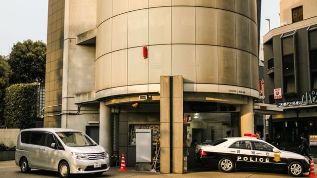 Street view featuring police and Nissan vehicles parked by a modern building.
