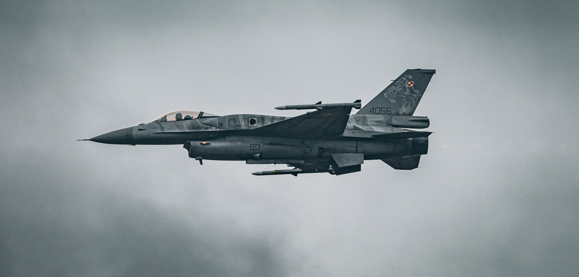 A dynamic capture of an F-16 fighter jet soaring through the sky over Hechtel-Eksel.