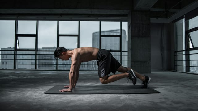 Fit man doing mountain climbers exercise inside a modern gym