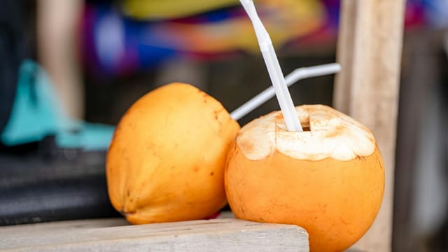 Close-up of fresh yellow coconuts with drinking straws, perfect for a tropical refreshment.