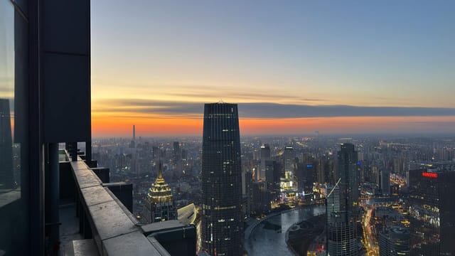 A breathtaking view of Shanghai's skyline during dusk with illuminated skyscrapers and a river.