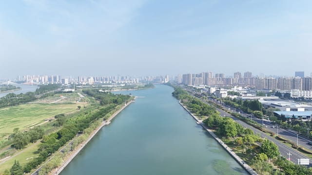 Aerial view showcasing a river flanked by a sprawling cityscape under a clear blue sky.