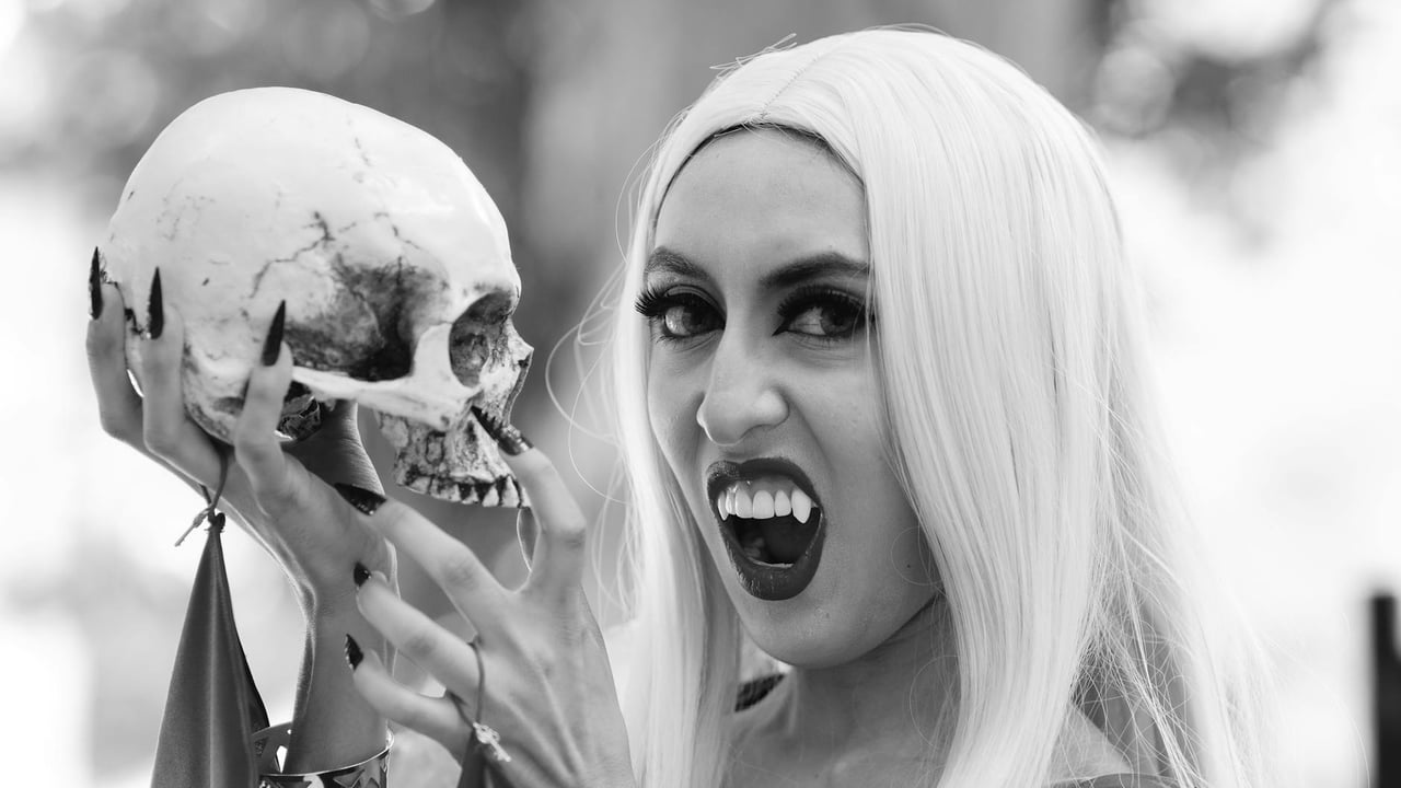 Black and white portrait of a vampire woman holding a skull, showcasing gothic Halloween style.