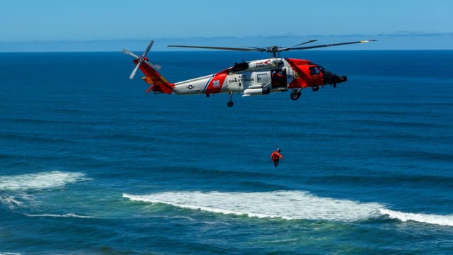Dramatic coast guard helicopter rescue operation over the ocean waves.