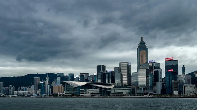 Stunning view of Hong Kong Island skyline with modern skyscrapers under a dramatic overcast sky.