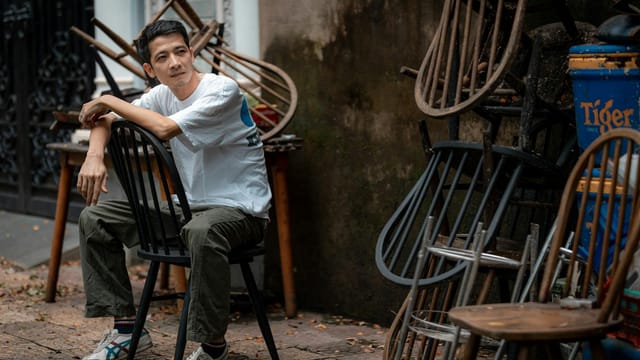Casual portrait of a man seated among stacked chairs in Bien Hoa, Vietnam.