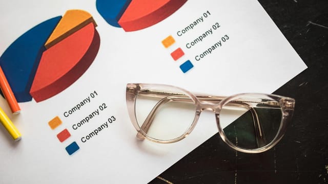 Photo of business charts and eyeglasses on a desk, ideal for finance and analytics themes.
