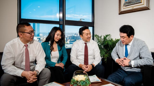 A group of business professionals engaging in a cheerful meeting in a modern office setting.