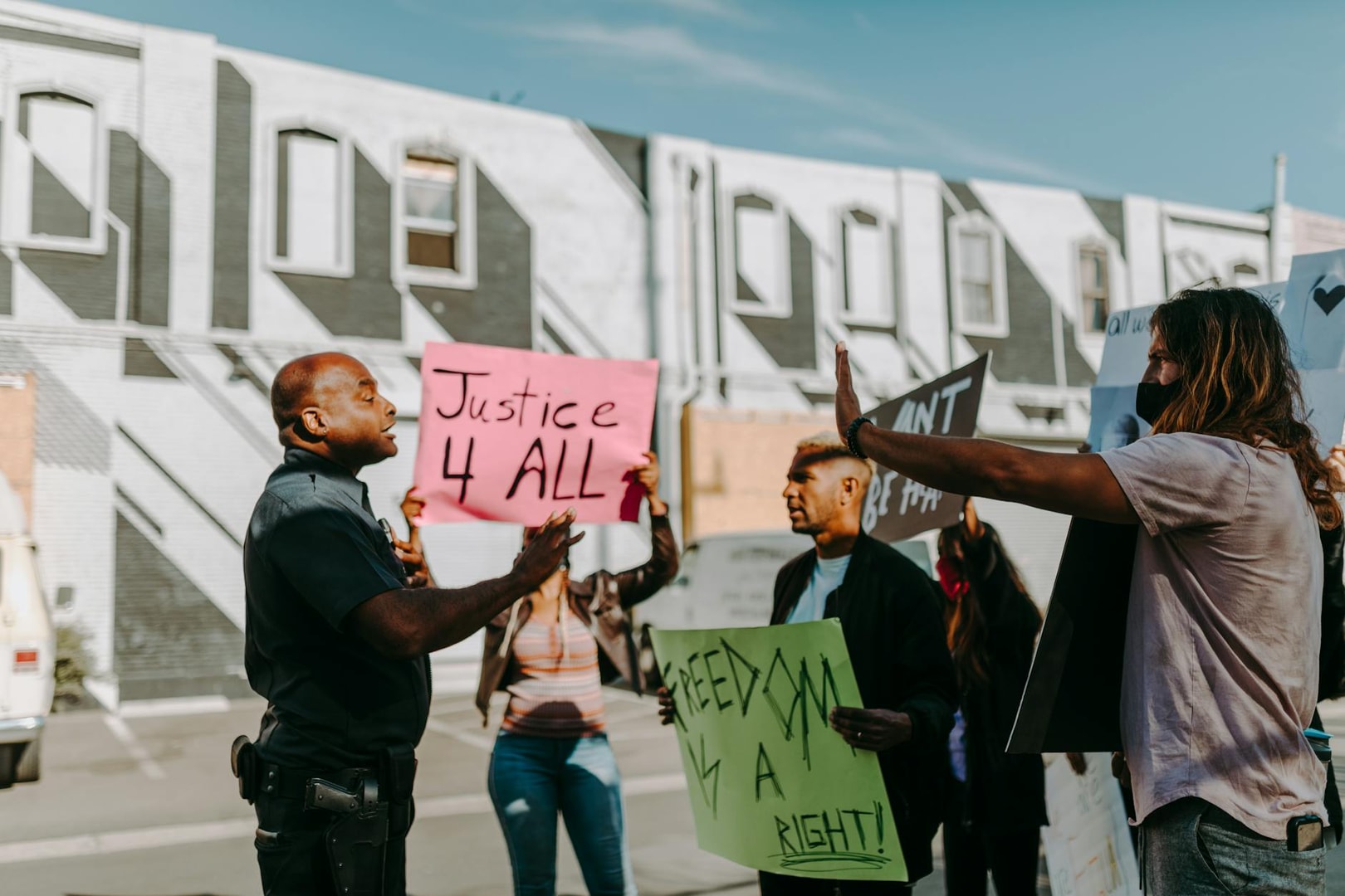 People hold signs during an outdoor protest, confronting a police officer.