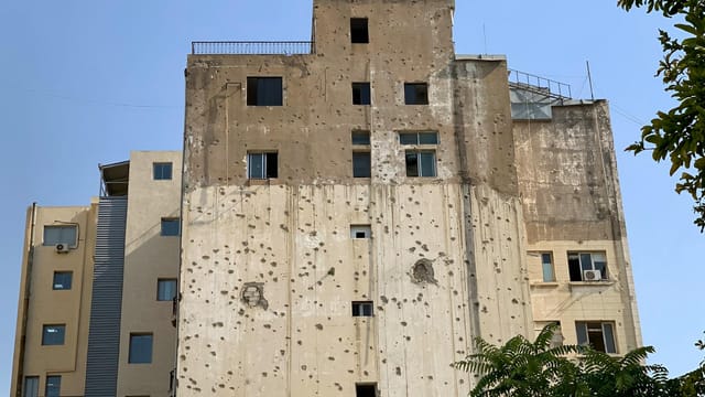 Old building facade in Beirut marked with bullet holes, showcasing war impact.