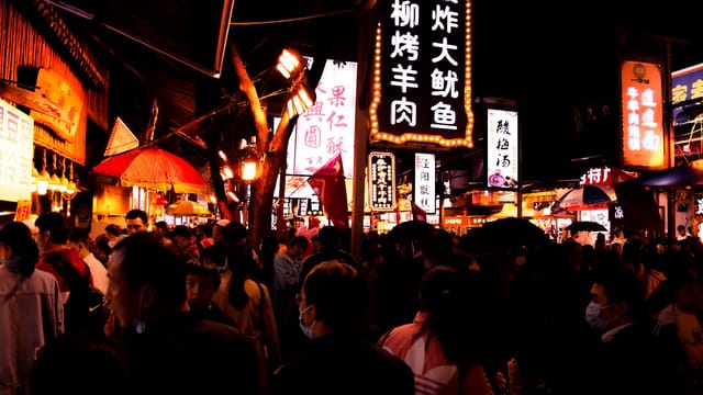 Bustling night market in Xi'an, Shaanxi, featuring illuminated signs and a lively crowd.