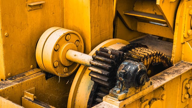 Detailed view of industrial machinery showcasing yellow painted metal gears and components.
