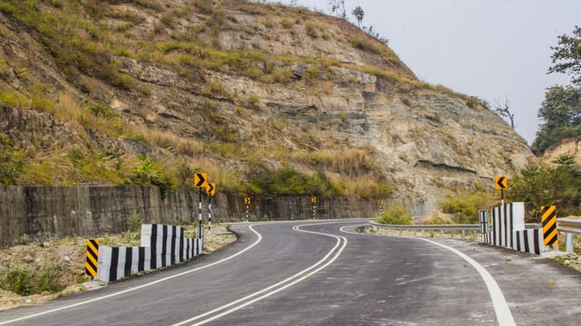 A scenic curved road through mountainous terrain under a clear sky, ideal for adventure travel.