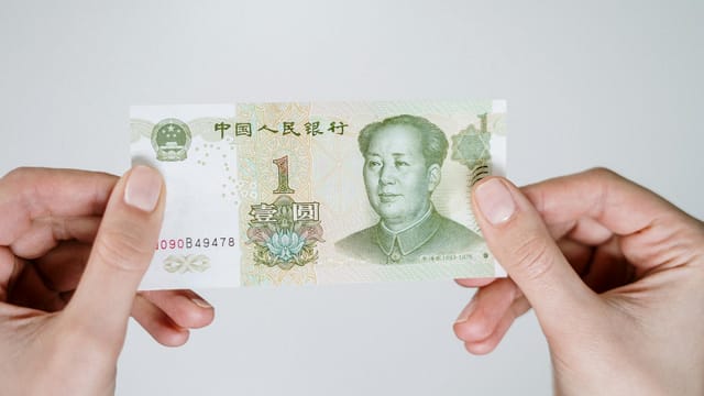 Close-up of hands holding a one Chinese Yuan note, showcasing currency details.