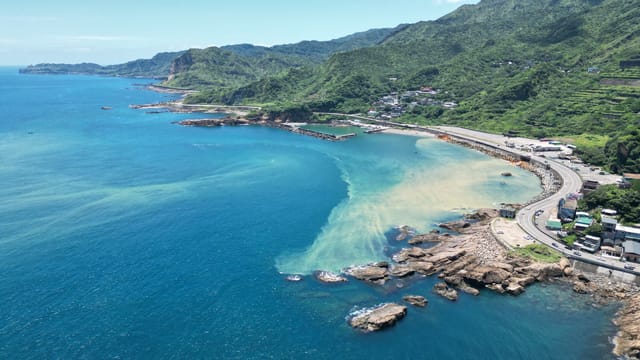 Stunning drone shot of Taiwan's vibrant coastline, showcasing blue waters and lush greenery.
