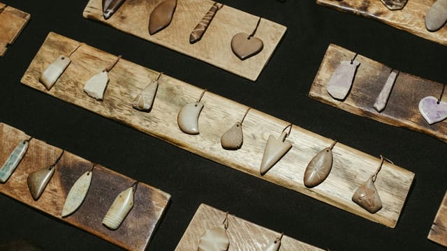 A collection of rustic stone pendants elegantly displayed on wooden boards, showcasing artisanal craftsmanship.