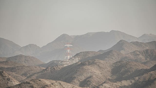 A transmission tower stands amidst the rocky hills of Dubai, UAE, creating a striking landscape.