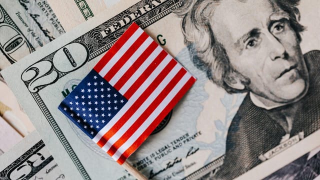 From above of small American flag placed on stack of 20 dollar bills as national currency for business financial operations