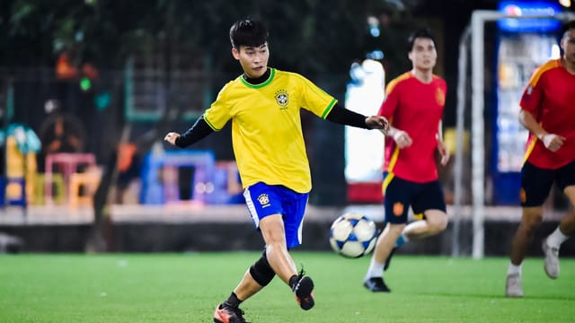 Dynamic soccer match in action at night in Hà Nội, showcasing young athletes playing on a vibrant field.