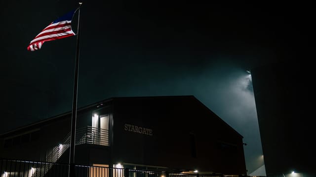 Dark atmospheric view of the Stargate building with an American flag at night.