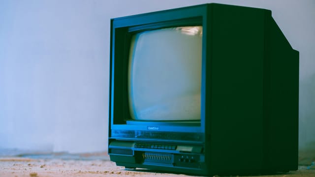 Aged television set with control panel and plastic case near wall in building on white background