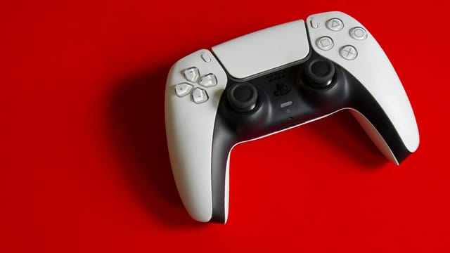 White DualSense controller for PlayStation 5 on a striking red backdrop, emphasizing modern gaming technology.