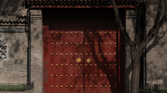 A historic red gate with gold studs, reflecting traditional Chinese architecture and culture.