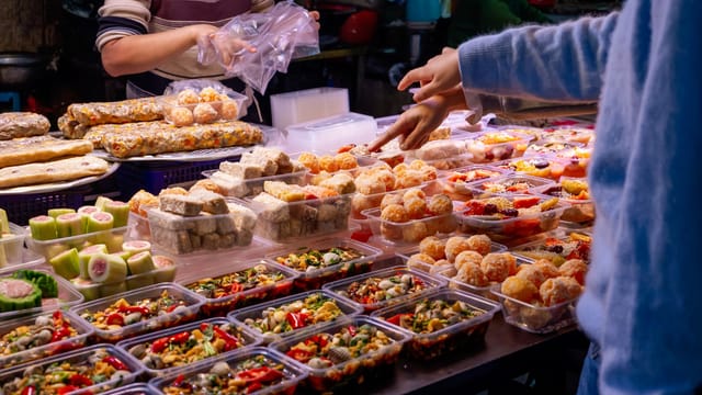 Colorful variety of street food in Jieyang, China, showcasing local culinary delights under bustling market lights.