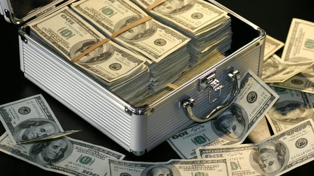 A metallic briefcase full of US dollar bills, symbolizing wealth and investment.