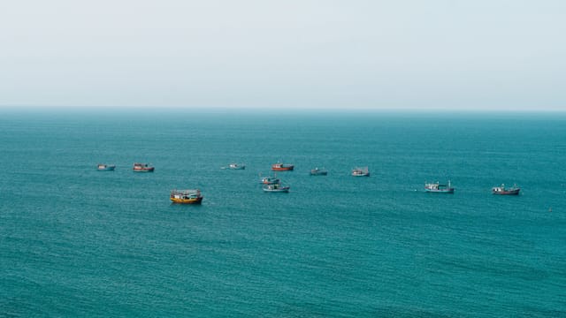 Aerial view of colorful fishing boats on the calm sea in Quang Ngai, Vietnam.