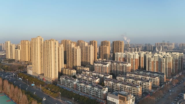 Aerial shot capturing a sprawling urban skyline with high-rise buildings in a clear daylight setting.
