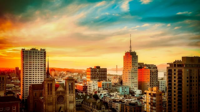 Stunning view of San Francisco cityscape with Golden Gate Bridge at sunset, vibrant urban atmosphere.
