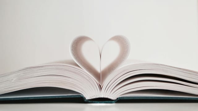 Close-up of open book with pages forming a heart shape, symbolizing love for reading.