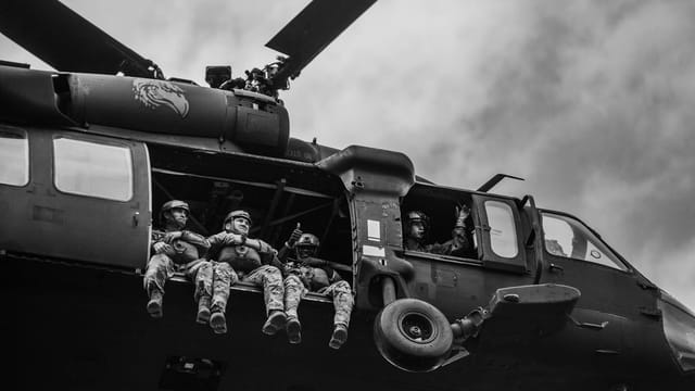 Black and white image of soldiers in a helicopter during flight.