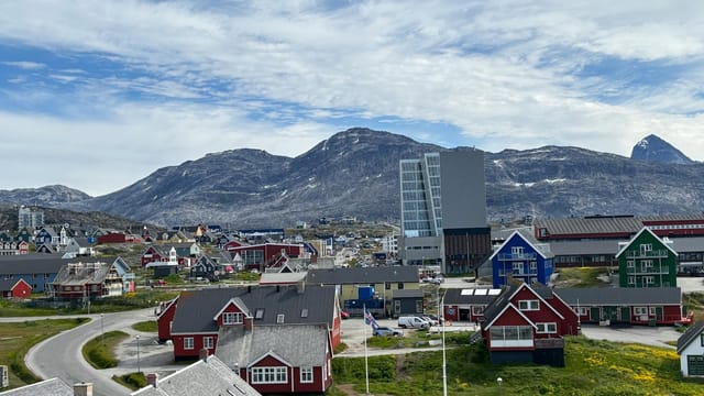 A picturesque view of Nuuk with colorful buildings against a mountainous backdrop.