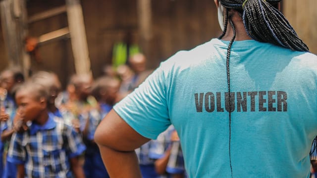 A volunteer interacts with children in a village school setting, fostering community support and development.