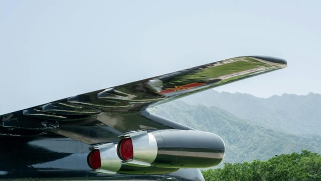 Close-up of an aircraft wing and engine against a mountainous backdrop.